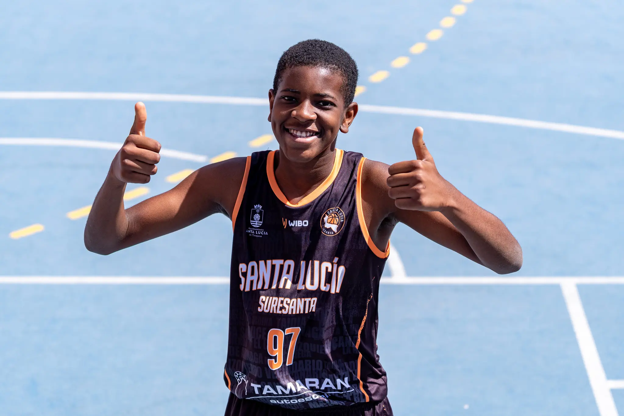 Jugador del club sonriendo y levantando los pulgares en la cancha exterior