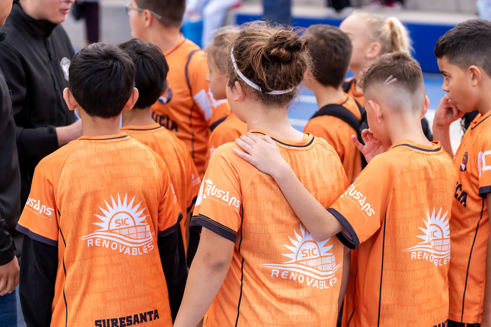 Equipo de canasta pequeña de espaldas, abrazados con la camiseta naranja del club